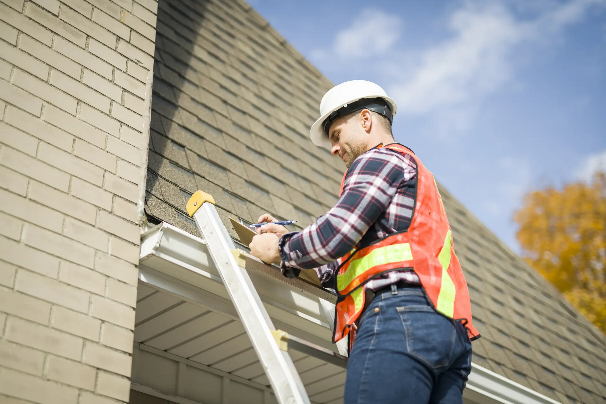 Worker repairing roof on ladder