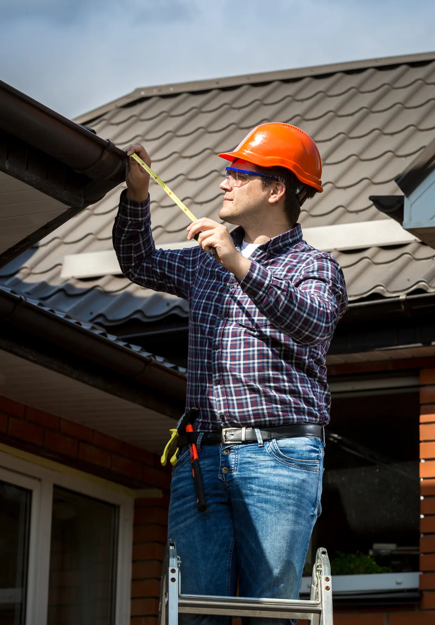 Construction worker inspecting roof gutters