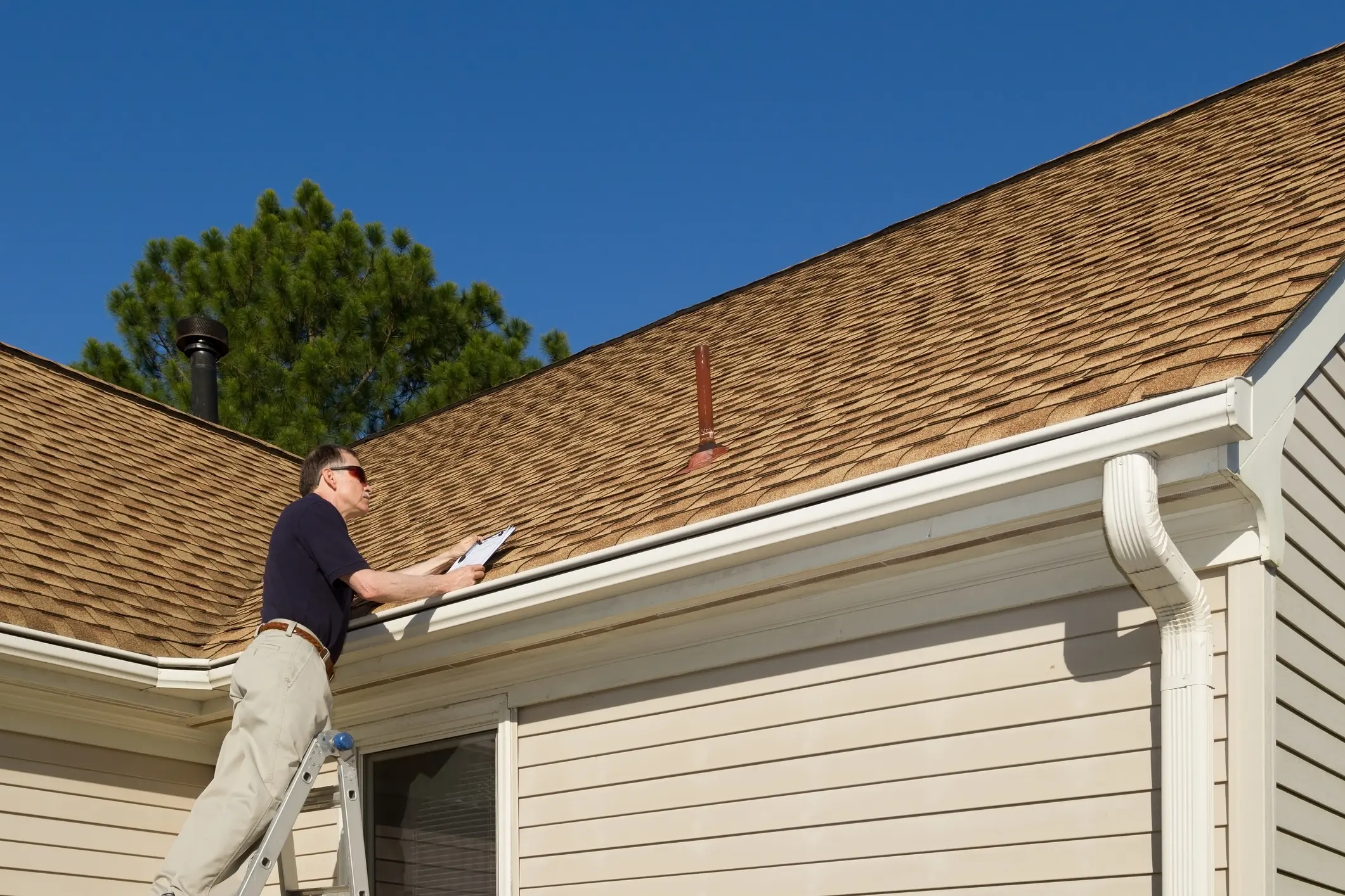 Man inspecting house roof with clipboard