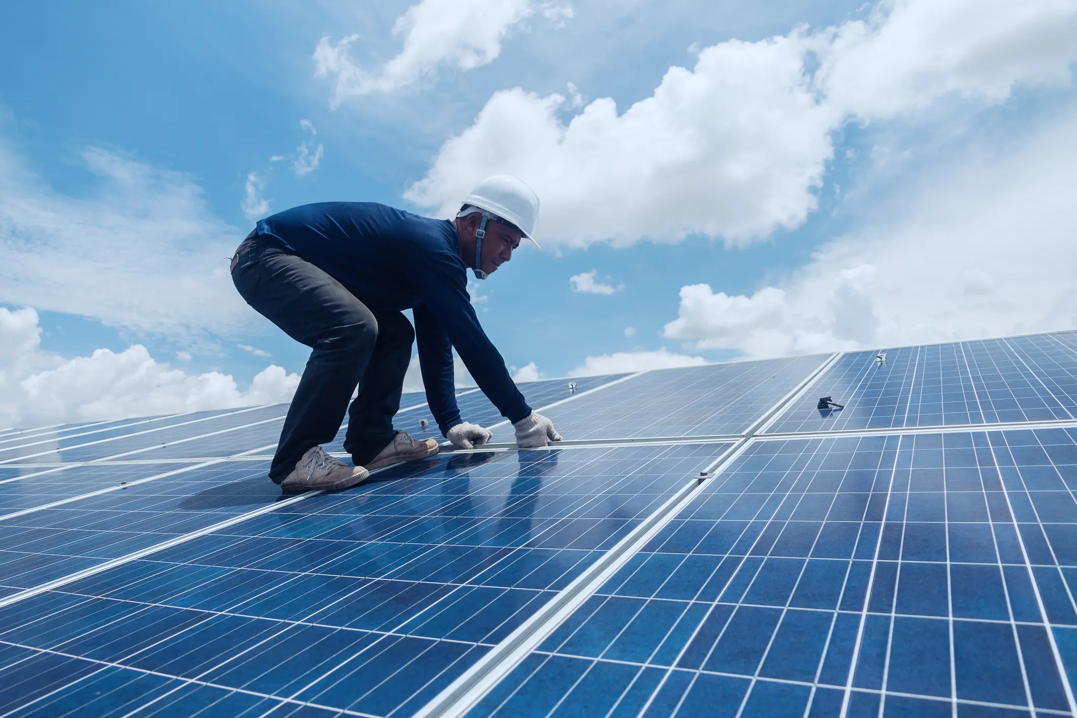Man adjusting solar panels on sunny day