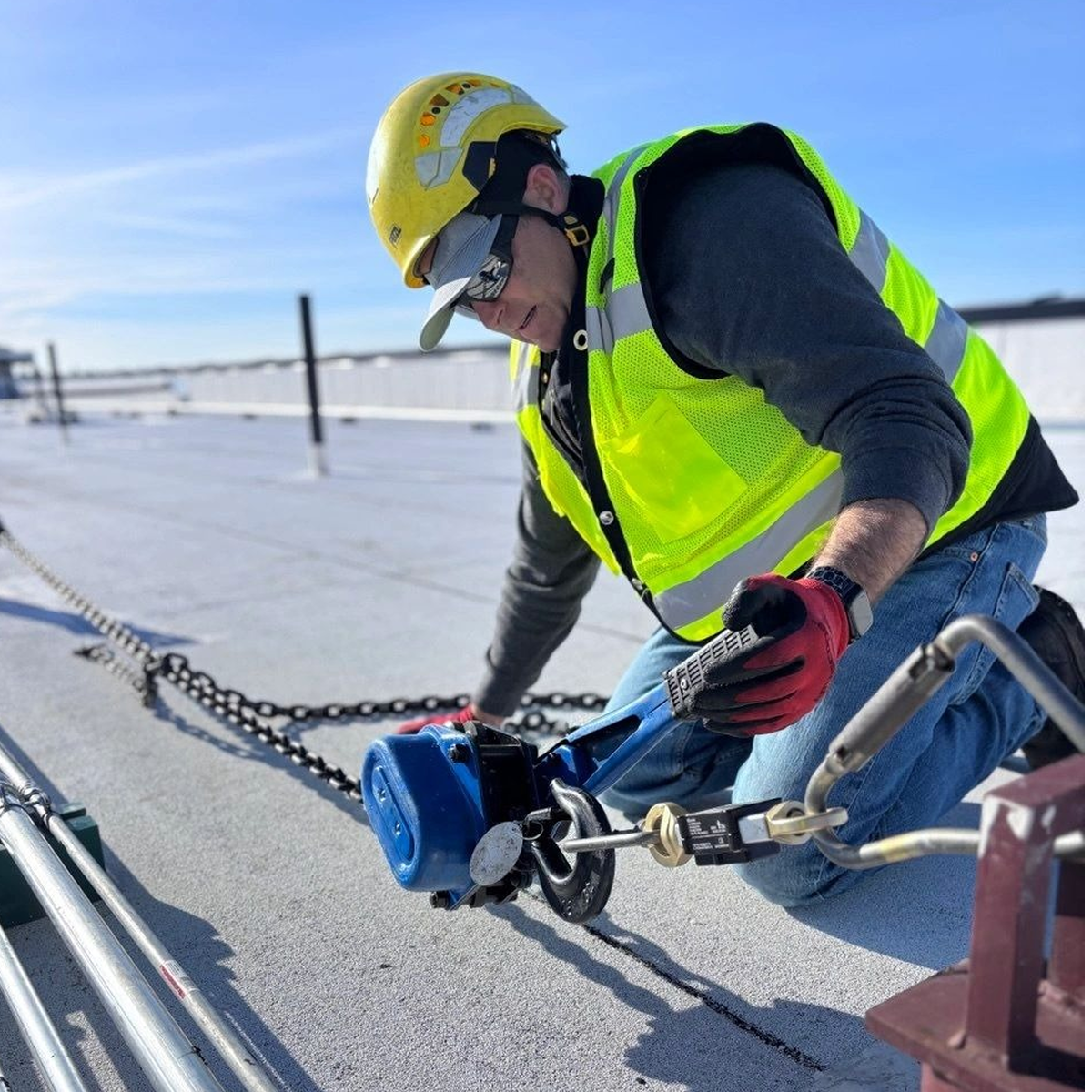 Construction worker securing safety equipment on roof.